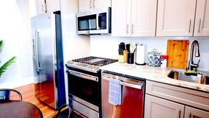 A modern kitchen with stainless steel appliances, a microwave, and a wooden cutting board. - Governors Apartment -  2 bedroom  - Steps to FQ (New Orleans)