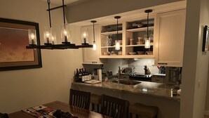 A kitchen with a dining area, featuring a wooden table, chairs, a chandelier, and cabinets above the counter. - Best Value. Large 2 Bedroom Condo in Bigfork, Montana. Perfect Summer Getaway!  (Bigfork)