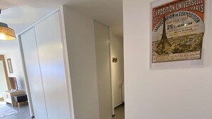 Un corridoio con una porta bianca, un poster incorniciato al muro e un pavimento piastrellato.