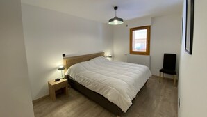 Una camera da letto con un letto, lampade ai comodini, una finestra e una sedia.