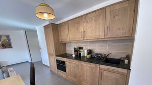 Una cucina moderna con mobili in legno, un piano di lavoro nero e un lampadario.