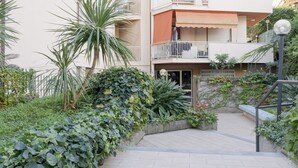 Un edificio residenziale con un balcone, una scala e un'area giardino con piante.