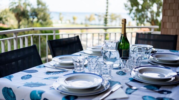 Tavola imbandita per la cena con piatti, bicchieri e una bottiglia di champagne, con vista su un panorama mozzafiato.