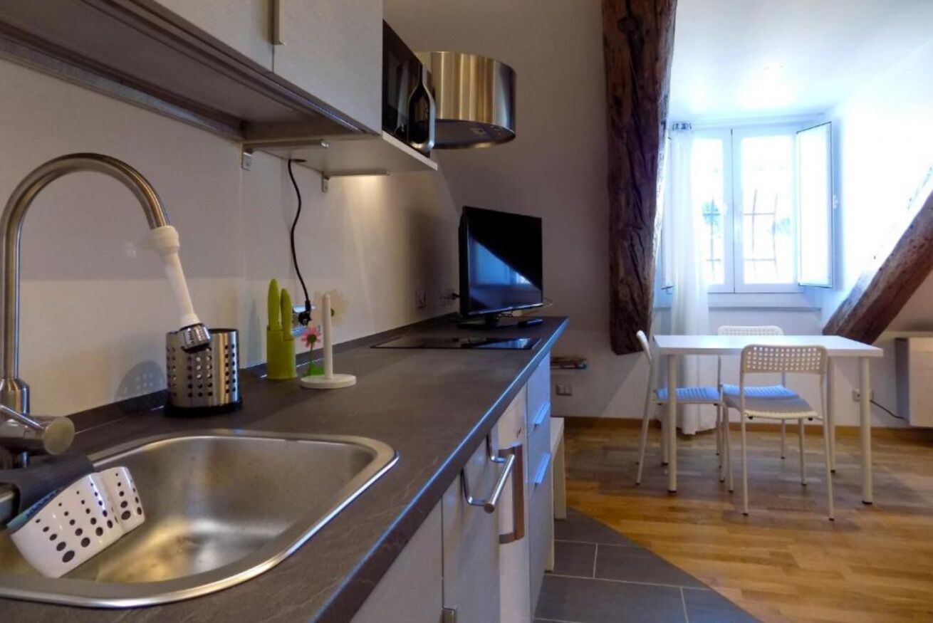 Una cocina con un lavaplatos, una estufa, un televisor y una zona de comedor con una mesa y sillas.