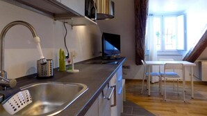 Una cocina con un lavaplatos, una estufa, un televisor y una zona de comedor con una mesa y sillas.