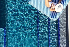 A pool with clear blue water, a striped lounge chair, and a white hat on the edge. - Pool House And Wave Hill House Lennox head (Lennox Head)
