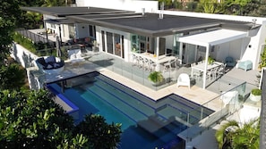 Ein modernes Haus mit Swimmingpool, Sitzgelegenheiten im Freien und einer überdachten Terrasse.