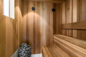 A sauna with wooden walls, benches, and a stone-filled container.