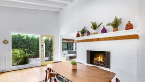 Ein moderner Essbereich mit Holztisch und -stühlen, einem Kamin und Blick ins Grüne.