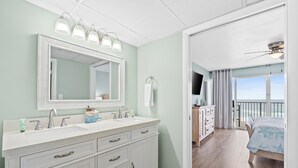 Une salle de bain avec un meuble-lavabo à deux vasques, un grand miroir et un ventilateur de plafond.
