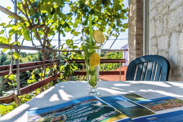 A table with a glass of drink, a menu, and a view of greenery. - Holiday apartment with air conditioning (Krnica)