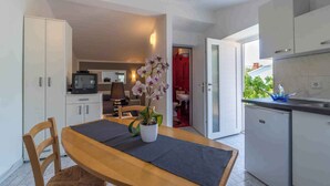 A modern kitchen with white cabinets, a wooden dining table, and a potted orchid.