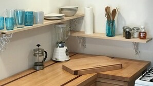 A kitchen with wooden countertops, a blender, shelves with jars and utensils, and a stove. - Sunnybrae Garden Studio (Arcata)