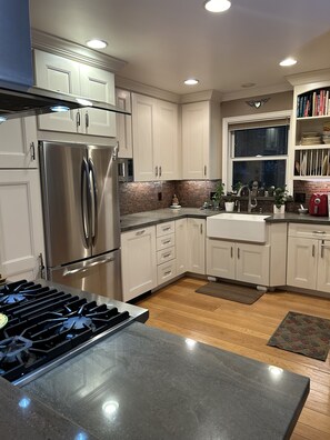 Uma cozinha moderna com eletrodomésticos de aço inoxidável, armários brancos e painel de backsplash de tijolos.