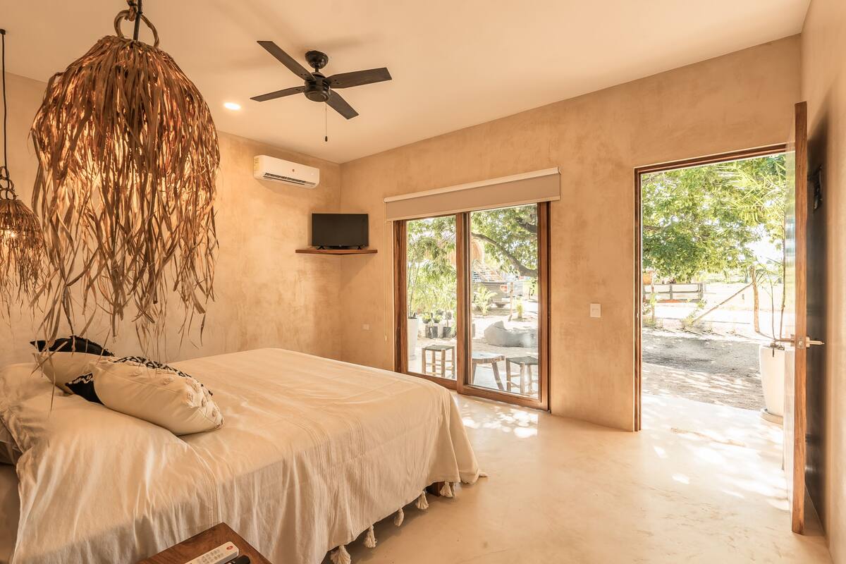 A spacious bedroom with a large bed, a ceiling fan, and a sliding glass door leading to an outdoor area.