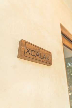 A wooden sign with the text "XCALAK" and the tagline "LIVE WELL - TRAVEL OFTEN" mounted on a wall. - Xcalak paradise Hotel (Xcalak)