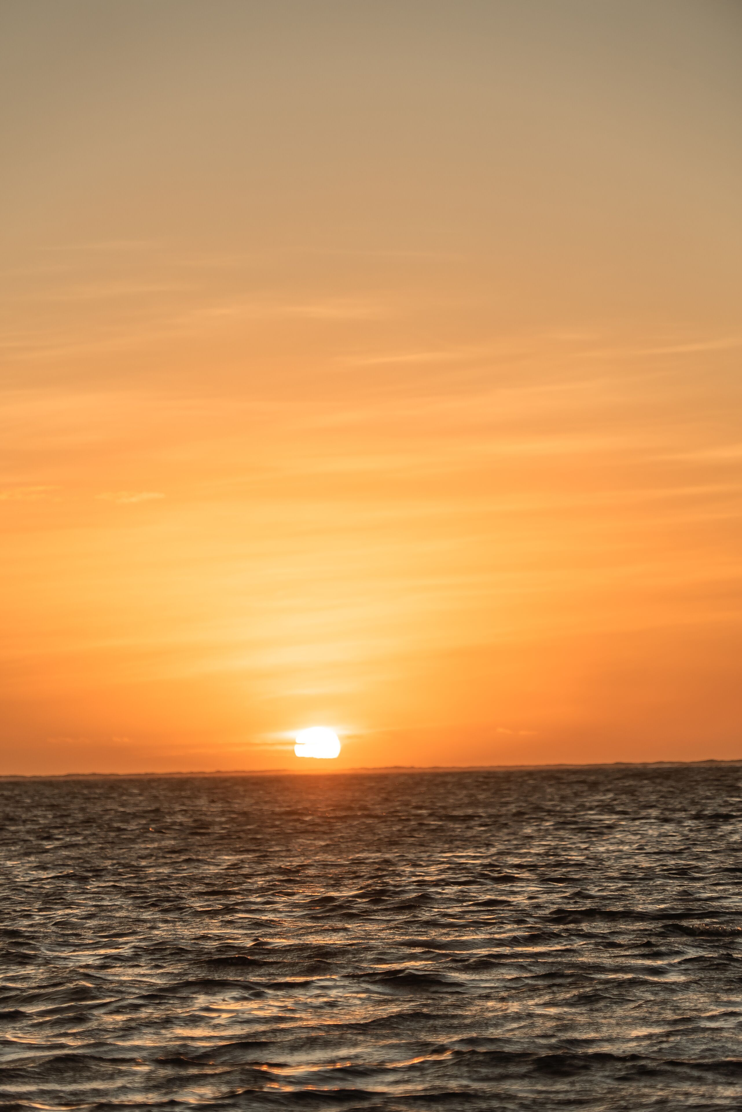 Una puesta de sol sobre el océano con aguas tranquilas.