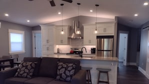 A modern kitchen with white cabinets, stainless steel appliances, and pendant lighting.