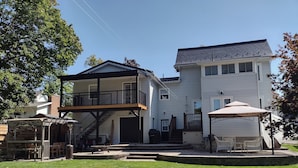 A two-story house with a balcony, a covered patio, and a well-maintained lawn.