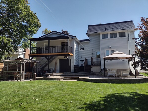 Une maison à deux étages dotée d’un balcon, d’un patio couvert et d’une pelouse bien entretenue.