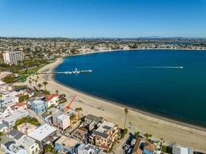 Un paysage urbain côtier avec une plage, des bâtiments et un port de plaisance.