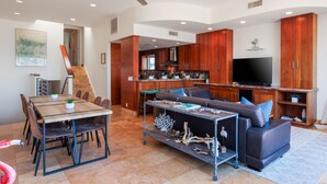 A spacious living area with a dining table, sofa, and a TV.