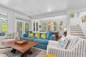 A spacious living room with a blue sofa, striped armchairs, and a wooden coffee table.