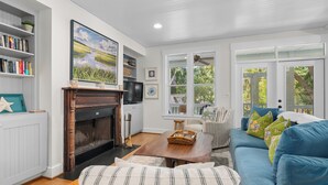 Una sala de estar con chimenea, televisor, estantería, sofá y ventana con vistas a zonas verdes.