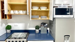 A compact kitchen with a gas stove, microwave, and cabinets. - 5 minutos Zona Rosa, Museos, Monumentos, Centros Comerciales. Casa Presidencial (San Salvador)