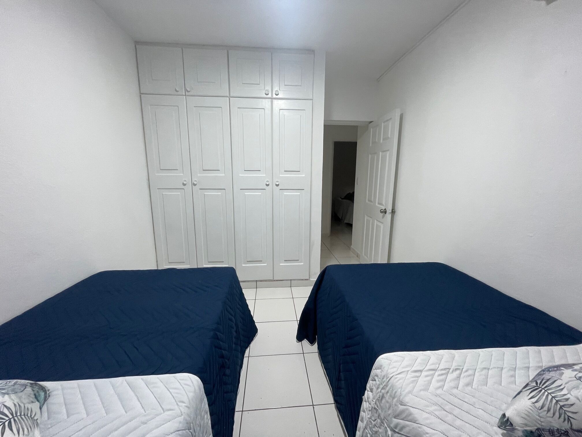 Una habitación con dos camas, paredes blancas y un armario grande.