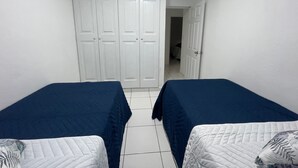 A room with two beds, white walls, and a large wardrobe. - 5 minutos Zona Rosa, Museos, Monumentos, Centros Comerciales. Casa Presidencial (San Salvador)