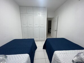 Una habitación con dos camas, paredes blancas y un armario grande.