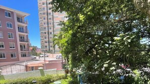 A well-maintained garden with a lawn, a metal table, and chairs, surrounded by a low wall and trees. - 5 minutos Zona Rosa, Museos, Monumentos, Centros Comerciales. Casa Presidencial (San Salvador)