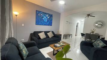 A modern living room with a sofa set, a coffee table, and a painting on the wall.