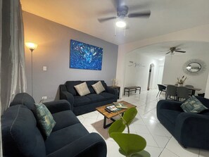 Una sala moderna con un conjunto de sofás, una mesa de centro y un cuadro en la pared.