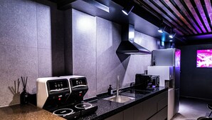 A modern kitchen with a built-in stove, sink, and a large flat-screen TV mounted on the wall. - U STAY MyeongDong (Seoul)