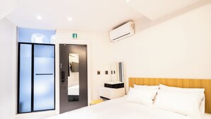 A modern hotel room with a large bed, a bedside table, a mirror, a wardrobe, and an air conditioning unit. - U STAY MyeongDong (Seoul)