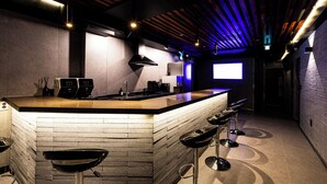A modern kitchen with a bar area, featuring a brick backsplash, stainless steel appliances, and bar stools. - U STAY MyeongDong (Seoul)