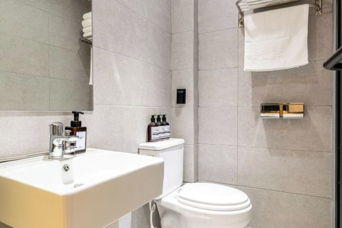 Un baño moderno con lavamanos, inodoro y toallero blancos.