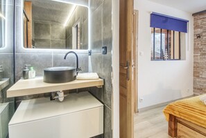 A modern bathroom with a large mirror, a black sink, and a wooden vanity.