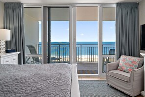 Une chambre d’hôtel comprenant un lit, un canapé, une télévision, un bureau et un balcon avec vue sur la plage.