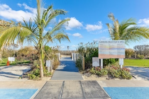 Ein Weg, der zu einer Strandbar und einem Grill führt, mit einem Schild, das die Annehmlichkeiten auflistet.