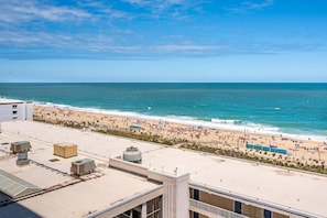 Une vue sur la plage depuis un point de vue élevé, incluant un toit avec des unités de climatisation et un bâtiment doté d’un toit plat.
