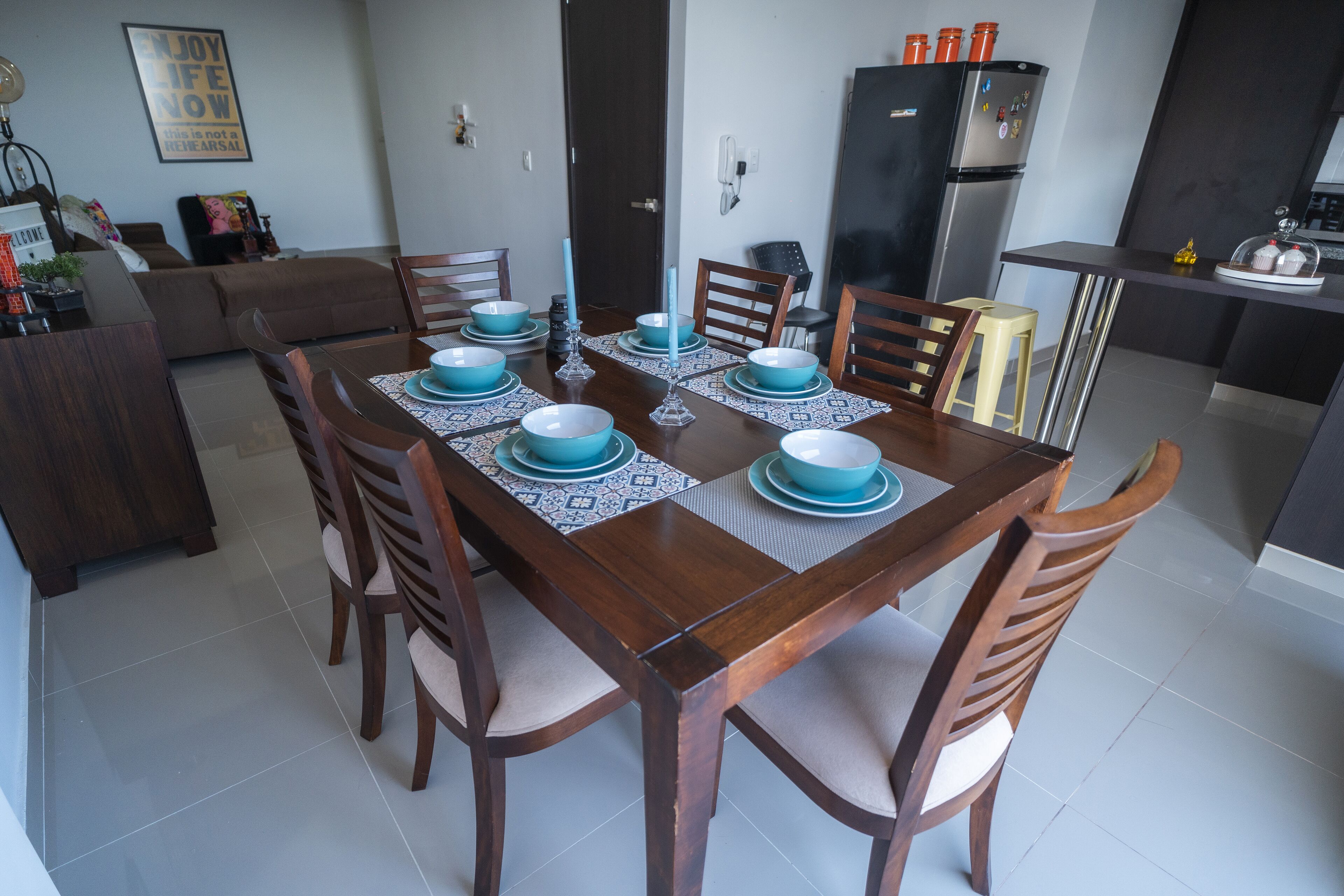A dining area with a wooden table set for four, surrounded by chairs.