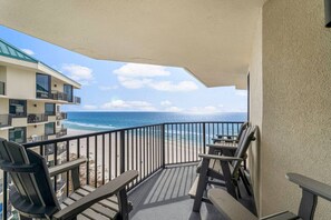 A balcony with a view of the ocean, equipped with outdoor furniture and a covered area. - Fun N The Sun at Sunbird 1102W | Beach Chair Service Included | Oceanfront & Ocean View | 3 Pools (Panama City)