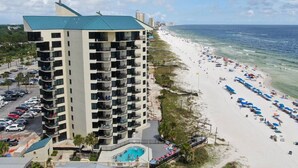 A high-rise hotel with multiple balconies, a swimming pool, and a beach with umbrellas. - Fun N The Sun at Sunbird 1102W | Beach Chair Service Included | Oceanfront & Ocean View | 3 Pools (Panama City)