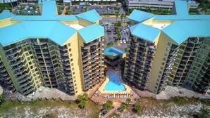 A high-rise hotel with multiple balconies, a central swimming pool, and a beach area. - Fun N The Sun at Sunbird 1102W | Beach Chair Service Included | Oceanfront & Ocean View | 3 Pools (Panama City)