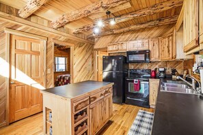 Eine Küche mit Holzschränken, einem Kühlschrank, einer Mikrowelle, einem Herd und einem Spülbecken.