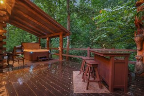 A wooden deck with a hot tub, bar area, and seating. - Arrowhead Lodge | Hocking Hills, Hot Tub, 5 Acres (Logan)