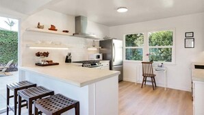Une cuisine moderne avec des meubles blancs, un îlot central et un coin repas comprenant une chaise et une table.